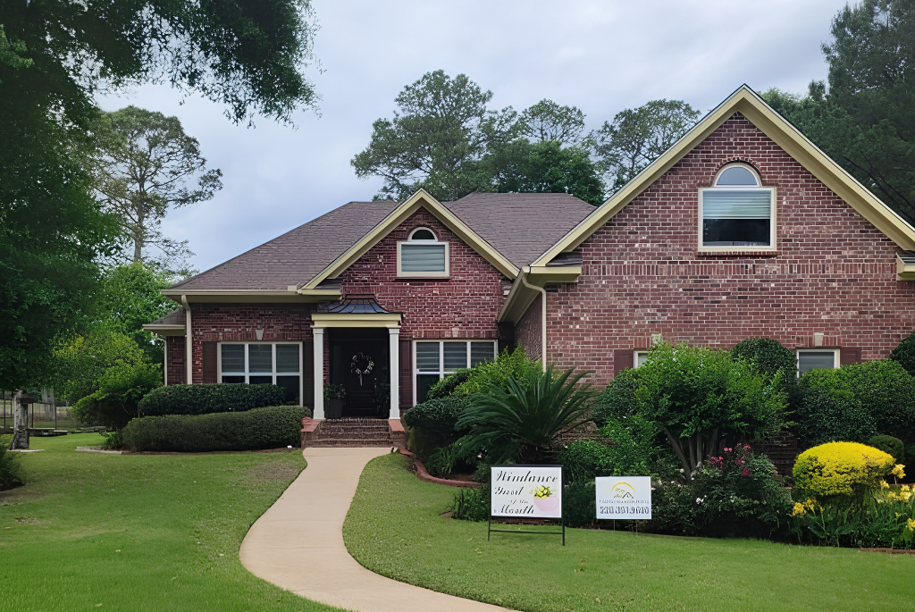 Brick suburban house with a curved walkway to the front door, manicured lawn, and two yard signs in the front yard.